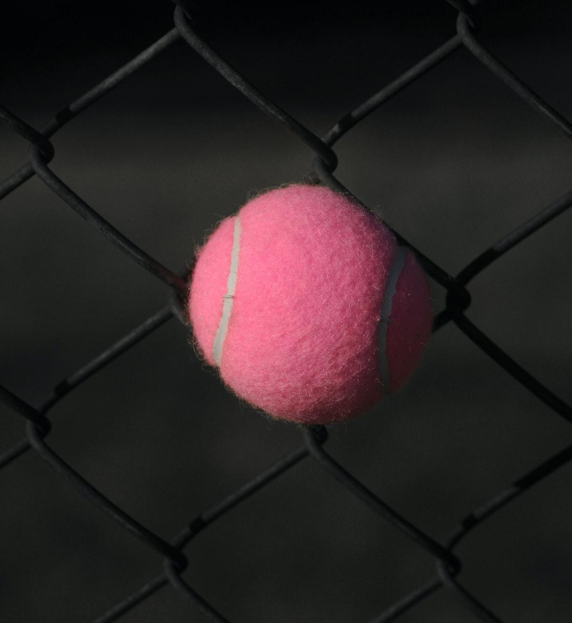 red tennis ball on gray steel fence